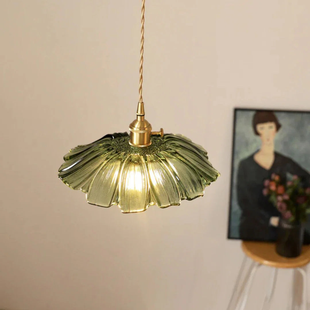 Decorative pendant light with a floral glass shade in a room setting.