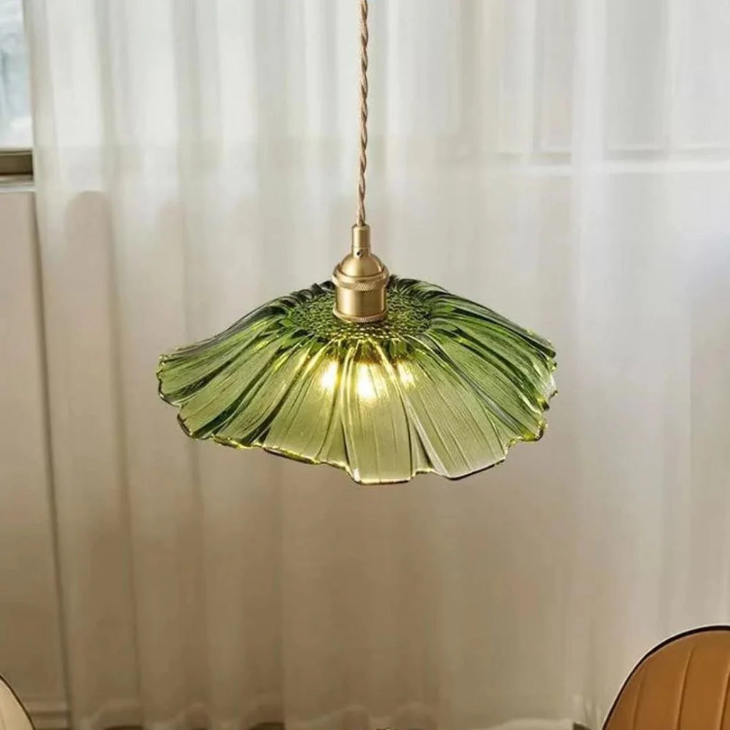 Green glass pendant light with gold fixture against a white curtain background