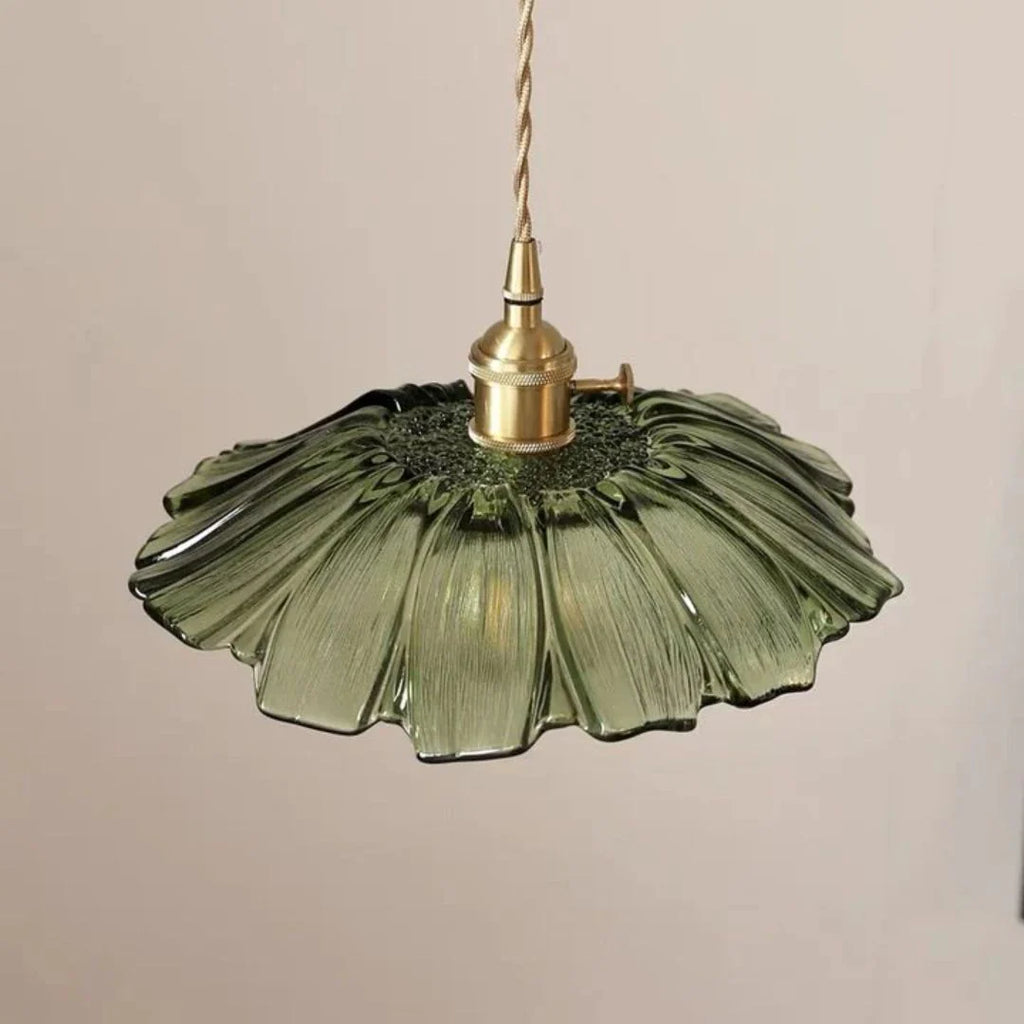 Green glass pendant light with brass fitting on a beige background