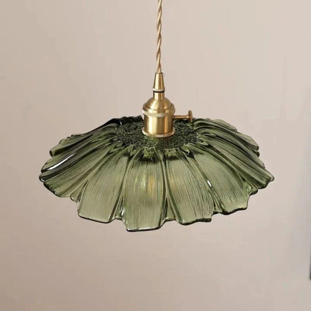 Green glass pendant light with brass fitting on a beige background