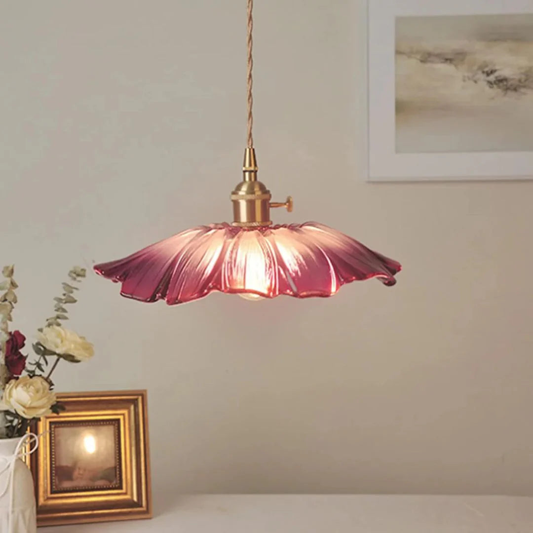Purple pendant light with gold fixture on a neutral wall with decor elements.