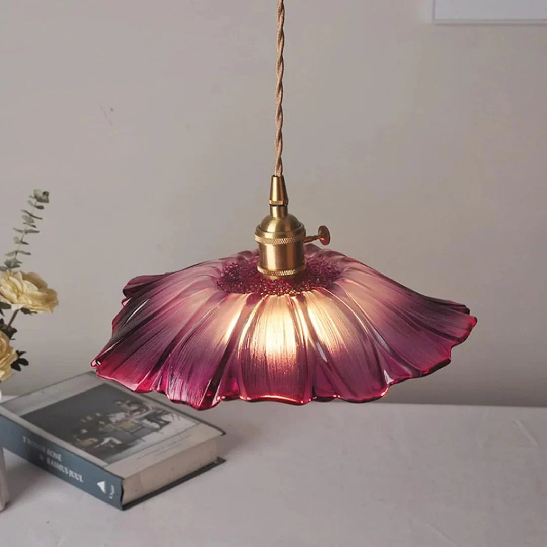 Floral-patterned pendant light with a purple glass shade on a white surface.
