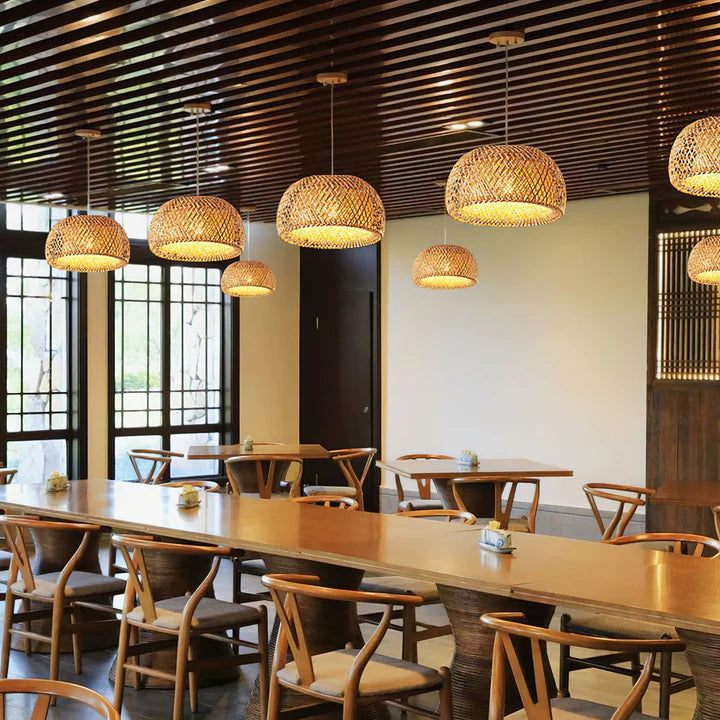 Modern dining area with wooden tables and chairs, and bamboo pendant lights.