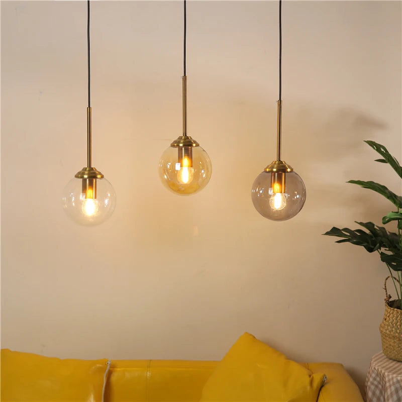 Three pendant lights hanging above a yellow sofa with a plant in the corner.