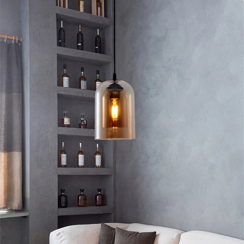 Pendant light with a amber glass shade hanging in a room with shelves and a sofa.