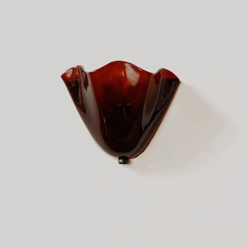 Burgundy glass wall sconce on a beige background