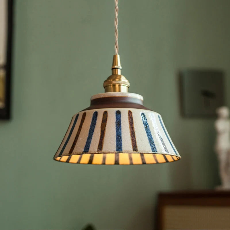 Pendant light with striped shade against a green wall