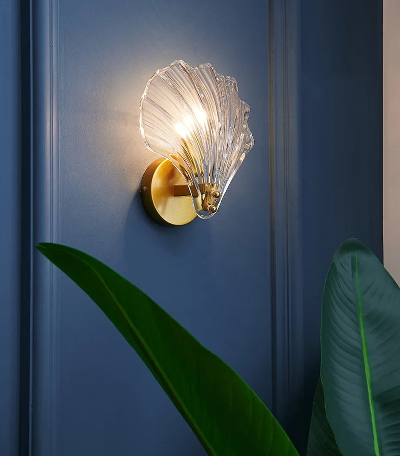 Decorative shell shaped wall sconce illuminating over a plant