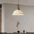 Pendant light fixture with decorative glass shade in a room setting, featuring.