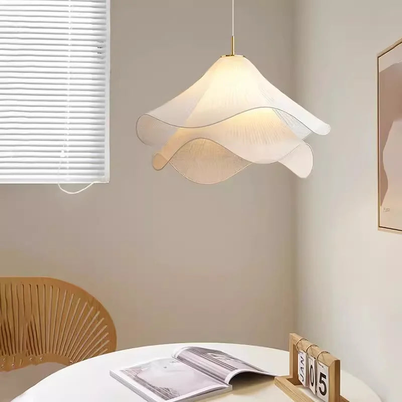 Modern pendant light hanging above a table with a book and calendar in a room.