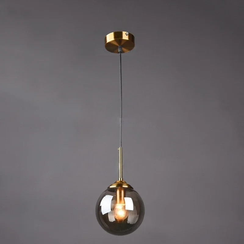 Grey pendant light with gold fixture and clear glass shade on a dark background