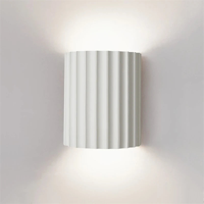 Wall-mounted light fixture with striped design on a plain wall