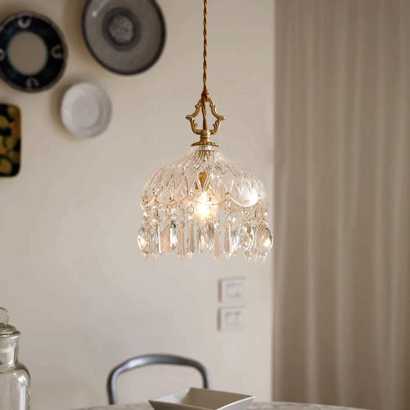 Crystal pendant light hanging in a room with decorative plates on the wall.