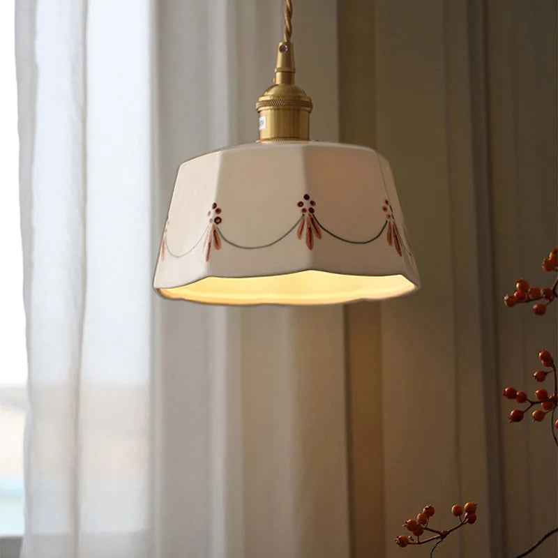 Decorative pendant light with a white shade and gold fixture against a neutral background.