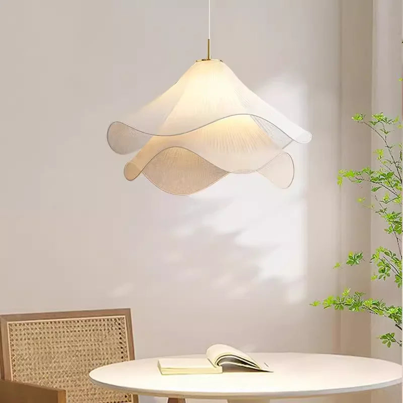 Modern pendant light fixture in a room with a table and plant