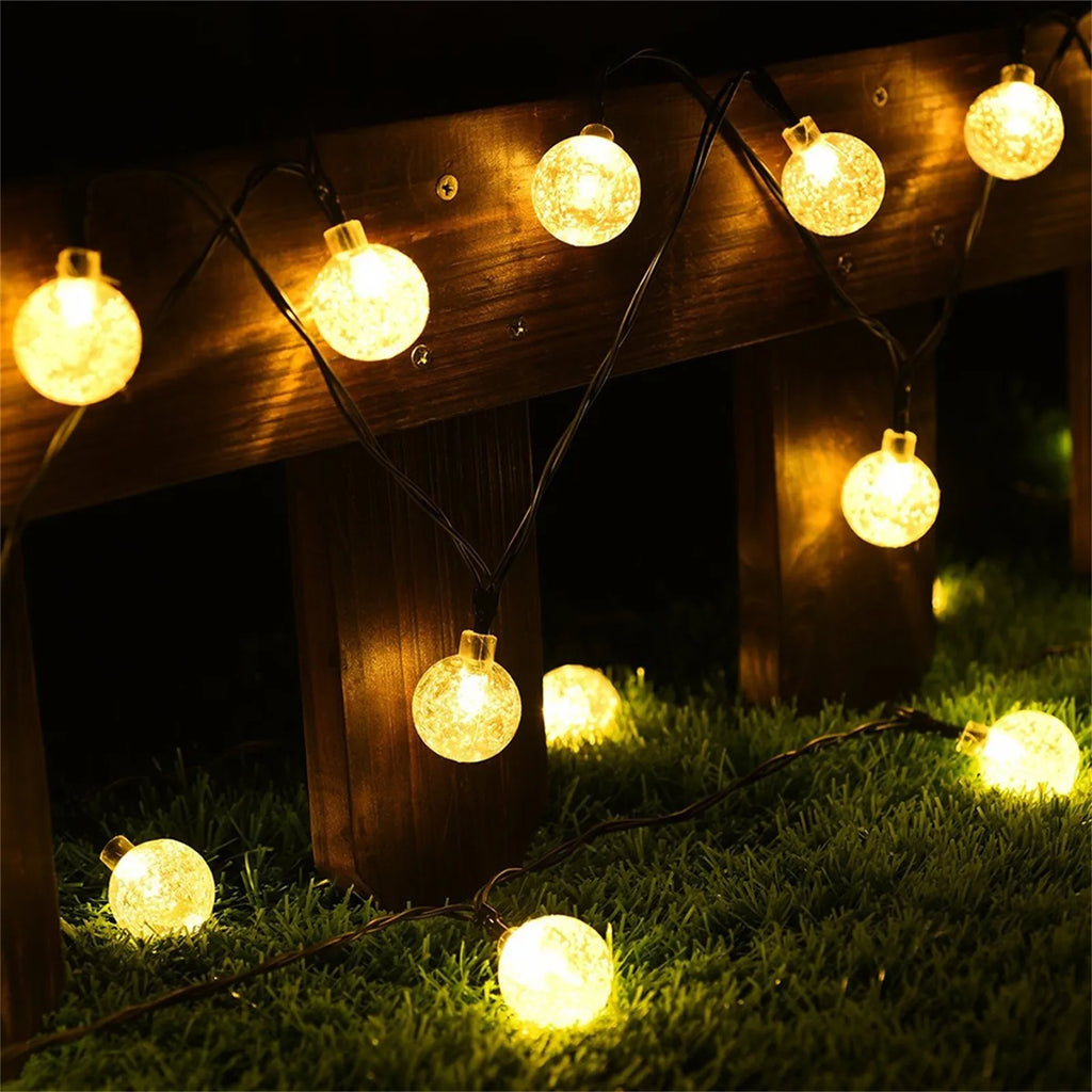 String of glowing outdoor lights on a wooden structure and grass