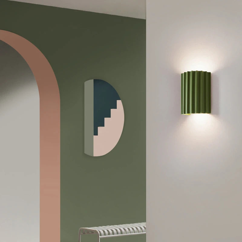 Modern wall lamp on a white wall with a green wall and archway in the background
