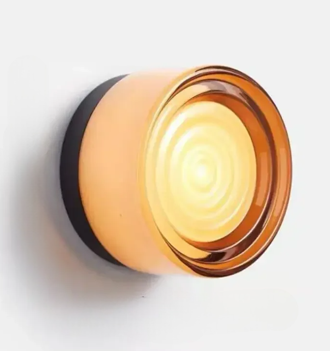 Round amber glass wall sconce with black base on a white background