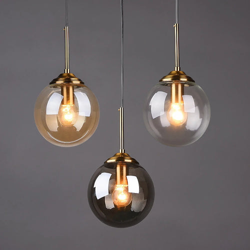 Three pendant lights with glass shades and gold fixtures on a dark background
