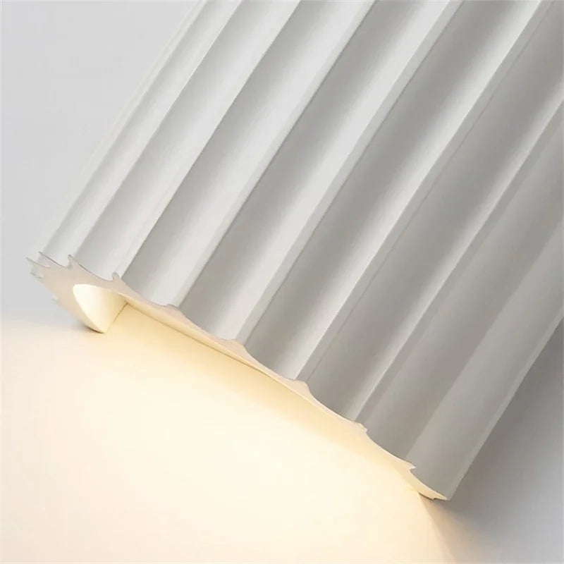 Wall-mounted light fixture with pleated design on a white background