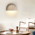 Modern interior with a travertine wall light fixture, wooden table, and chair.