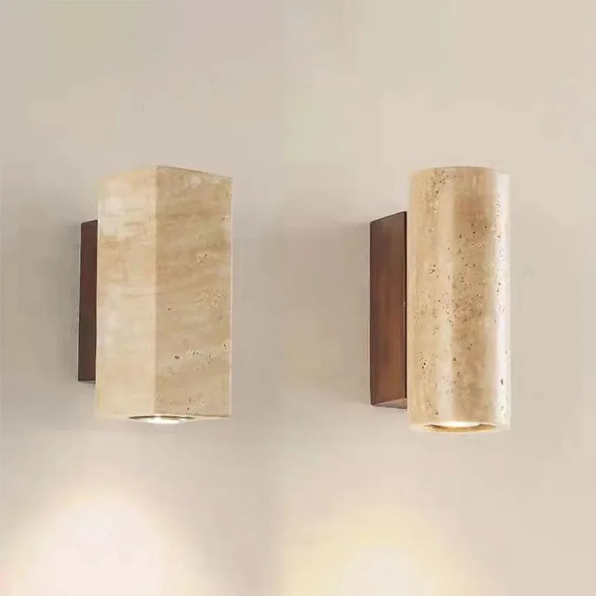 Two cylindrical wall lights with beige travertine finish and bronze base on a neutral wall.