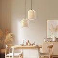 Dining room with wooden table, chairs, and pendant lights in a warm setting.
