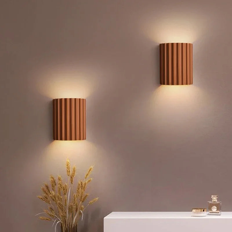 Two orange wall sconces on a neutral wall with decorative elements.