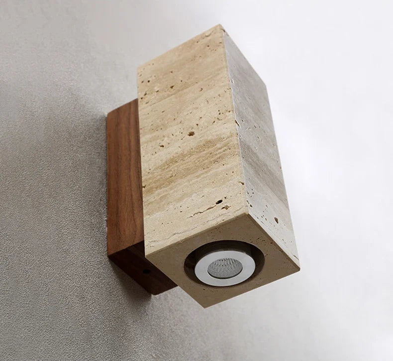 Modern wall light fixture with travertine and wood design on a grey wall.