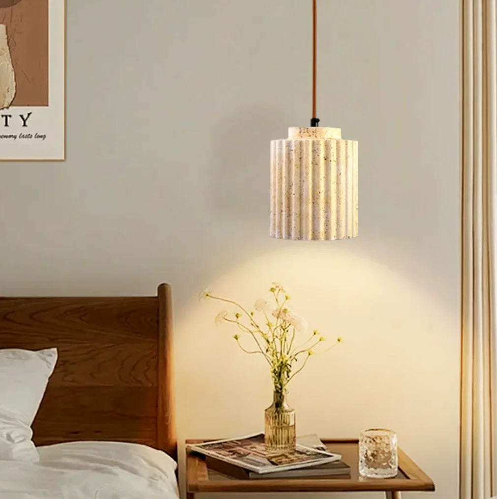 Bedroom with wooden headboard, pendant light, and small table with decorative items.