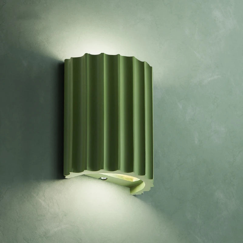 Green wall-mounted light fixture on a gray wall