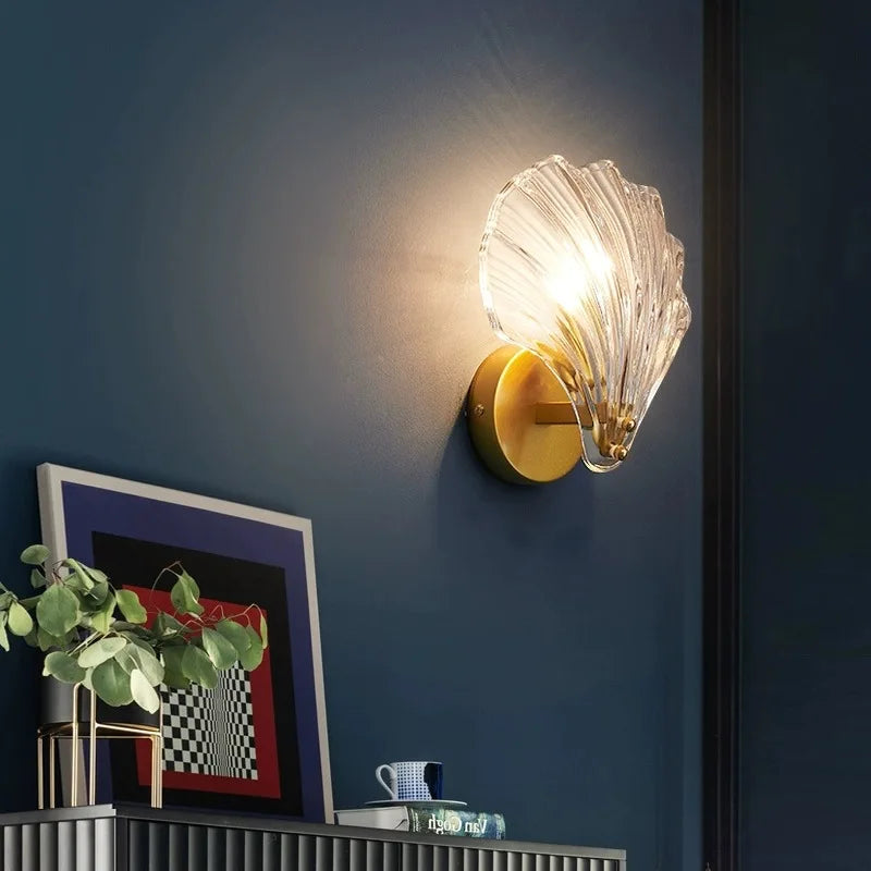 Side angle shot of glass shell shaped wall sconce illuminating desk underneath