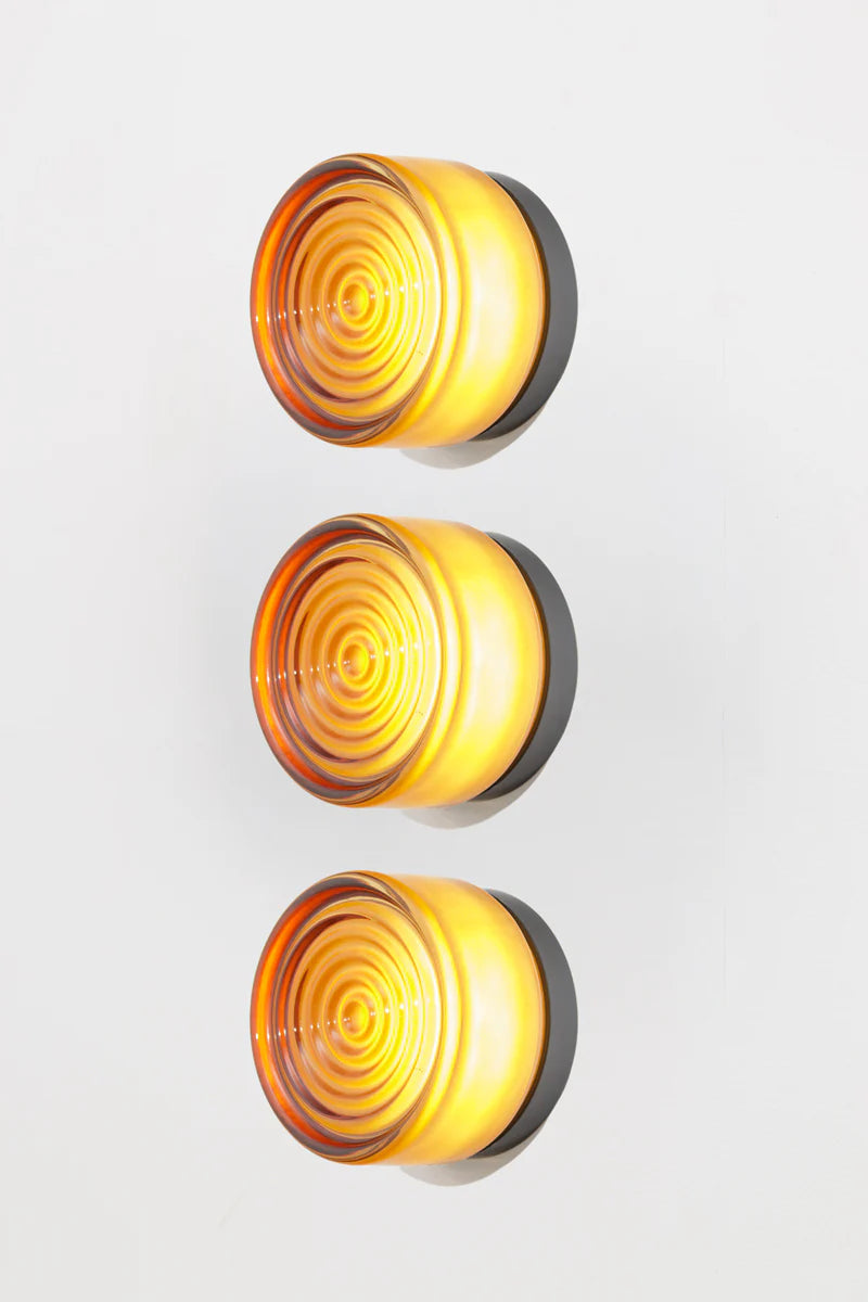 Three amber circular lights with a wavy pattern on a white background