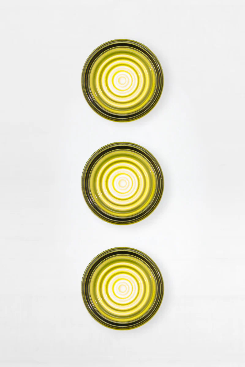 Three green glass wall sconces with concentric circle patterns on a white background